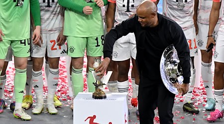 Bayern-Trainer Vincent Kompany stellt bei der Meisterparty eine Kakadu-Figur auf den Sockel. / Foto: Sven Hoppe/dpa
