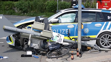 Ein Polizeiauto krachte in einen Ampelmast, der in einem Dominoeffekt umknickte und auf das Fahrrad eines Mannes stürzte.  / Foto: Goppelt/vifogra/dpa