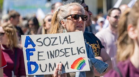 Eine Demonstrantin hält ein Plakat mit der Aufschrift «Asozial - Feindselig - Dumm» bei einer Demonstration gegen die AfD in München hoch. / Foto: Tobias Hase/dpa