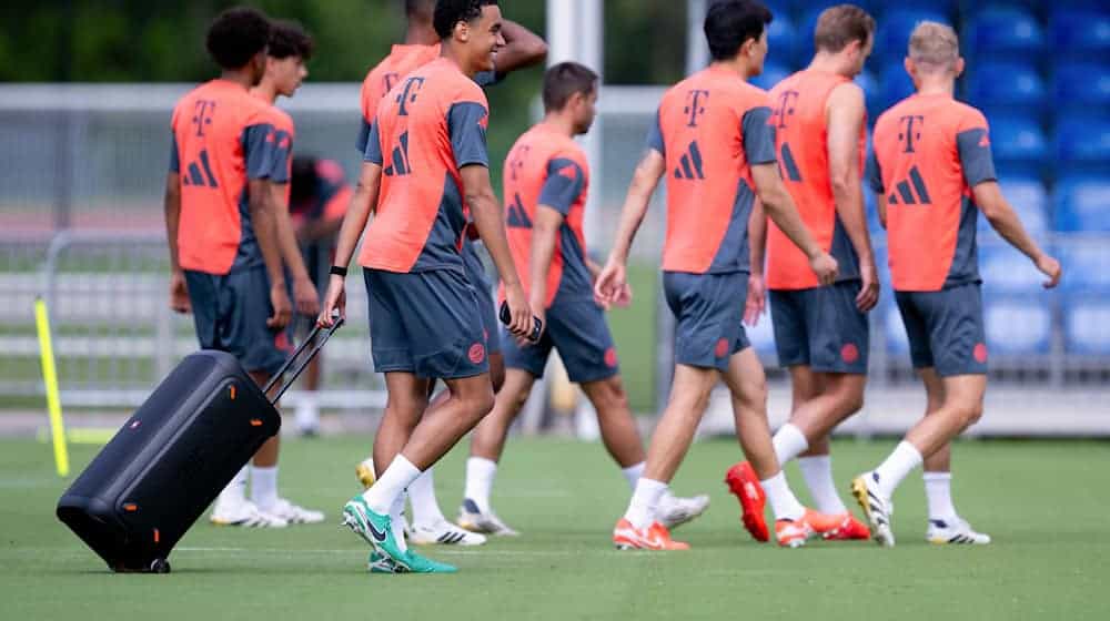 Jamal Musiala zieht beim Bayern-Training eine Musikbox auf den Platz. / Foto: Sven Hoppe/dpa