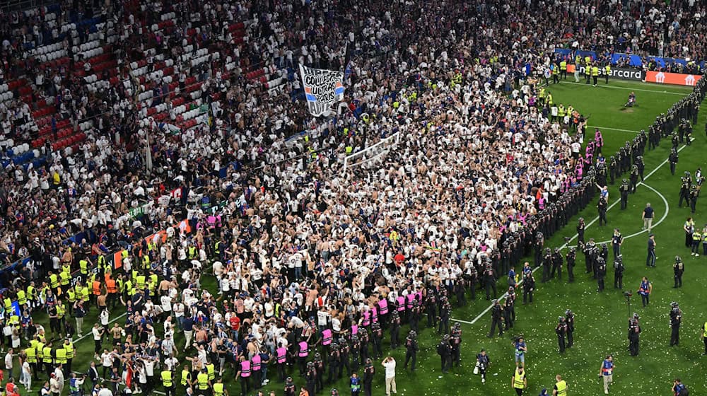 Party auf dem Rasen: Pariser Fans stürmen aus ihrem Block. / Foto: Peter Kneffel/dpa
