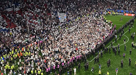 Party auf dem Rasen: Pariser Fans stürmen aus ihrem Block. / Foto: Peter Kneffel/dpa