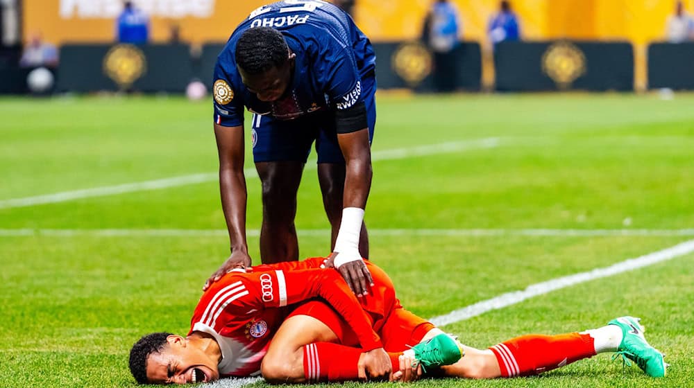 Jamal Musiala liegt mit starken Schmerzen verletzt am Boden. PSG-Profi William Pacho kümmert sich um ihn. / Foto: Malachi Gabriel/ZUMA Press Wire/dpa