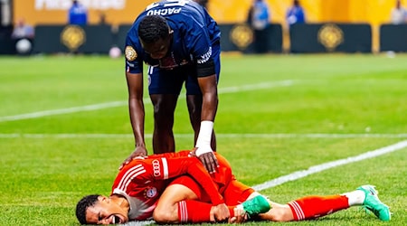 Jamal Musiala liegt mit starken Schmerzen verletzt am Boden. PSG-Profi William Pacho kümmert sich um ihn. / Foto: Malachi Gabriel/ZUMA Press Wire/dpa