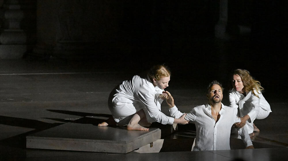 Der Jedermann (Philipp Hochmair) im Juli 2025 in seinem Grab - gehalten vom Glauben (Regine Zimmermann) und seinen Werken (Kathleen Morgeneyer). (Archivbild) / Foto: Barbara Gindl/APA/dpa