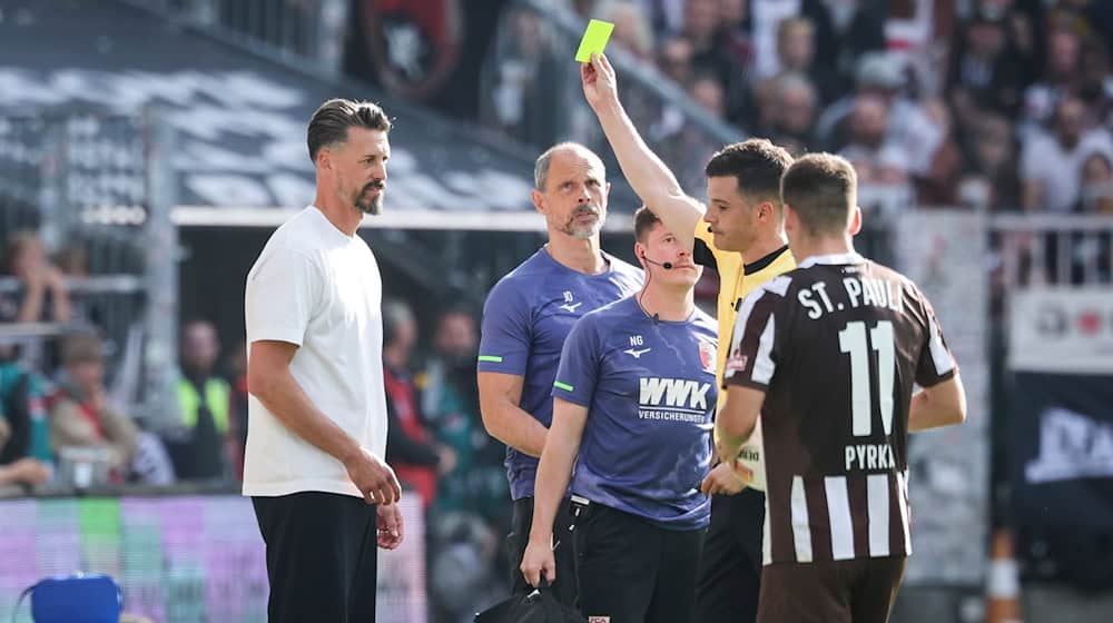 Schiedsrichter Harm Osmers zeigt Trainer Sandro Wagner (FC Augsburg, l) die gelbe Karte. / Foto: Christian Charisius/dpa