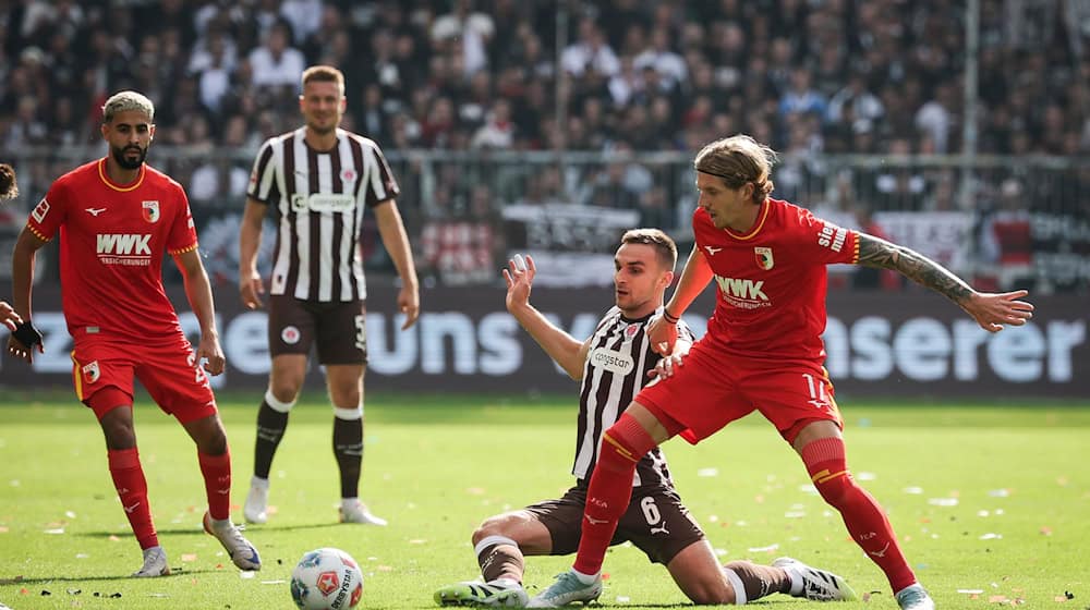 Im Zweikampf: Kristijan Jakić vom FC Augsburg (r) und St. Paulis James Sands. / Foto: Christian Charisius/dpa