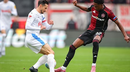 Kiel-Kapitän Steven Skrzybski (links) und Pape Demba Diop von Nürnberg kämpfen um den Ball. / Foto: Daniel Karmann/dpa