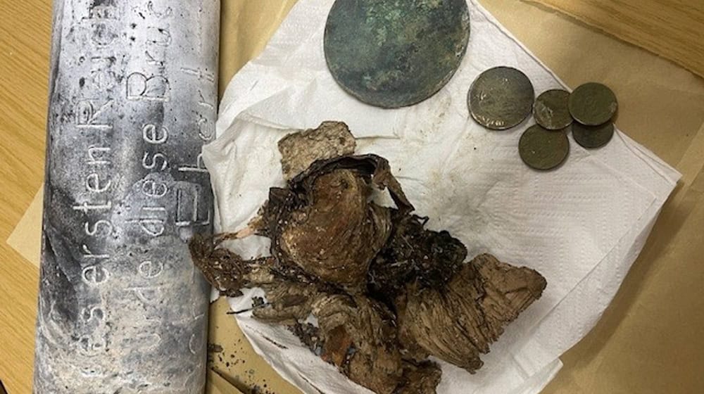 Silber- und Kupfermünzen, ein Zeitungsartikel und Fotos wurden seit dem beim Bau einer Brücke in Hof im Jahr 1928 in einer Zeitkapsel aufbewahrt. Nun sind die Gegenstände beim Abriss des Bauwerks wiedergefunden worden. / Foto: -/Stadt Hof/dpa