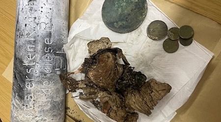 Silber- und Kupfermünzen, ein Zeitungsartikel und Fotos wurden seit dem beim Bau einer Brücke in Hof im Jahr 1928 in einer Zeitkapsel aufbewahrt. Nun sind die Gegenstände beim Abriss des Bauwerks wiedergefunden worden. / Foto: -/Stadt Hof/dpa