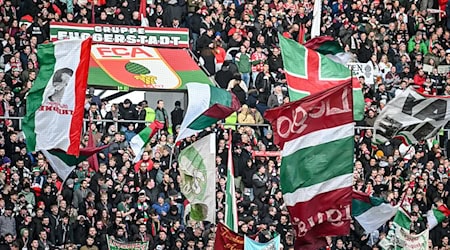 Fans des FC Augsburg schwenken ihre Fahnen in der WWK-Arena. (Archivfoto) / Foto: Harry Langer/dpa