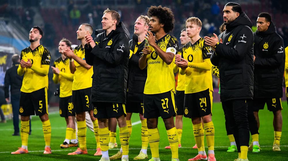 Hauptsache gewonnen: Dortmunds Spieler nach dem 1:0 in Augsburg vor ihren mitgereisten Fans.  / Foto: Tom Weller/dpa