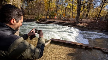 Freizeitsurfer Alexander Neumann fotografiert die - zurzeit nicht funktionstüchtige - Eisbachwelle im Englischen Garten. / Foto: Peter Kneffel/dpa