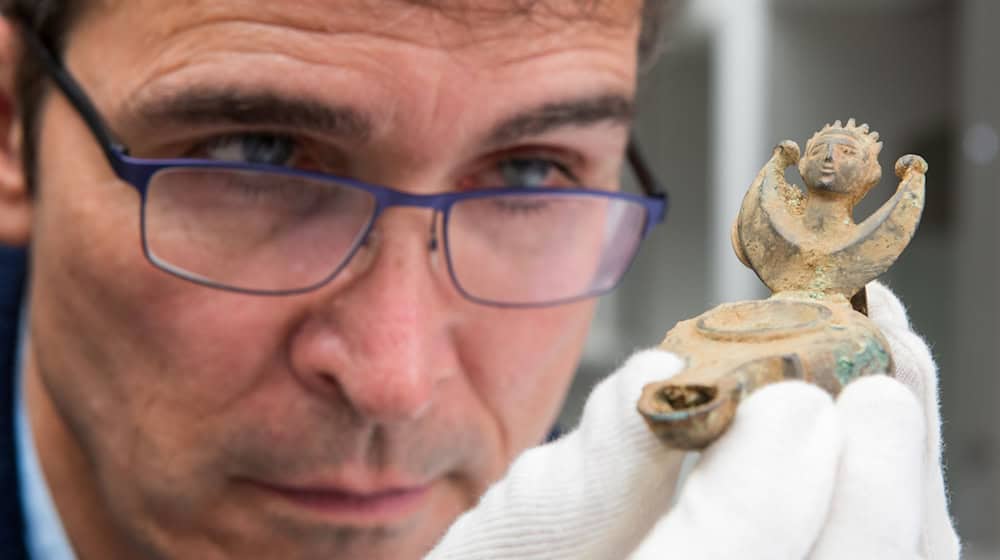 Augsburgs Stadtarchäologe Sebastian Gairhos betrachtet eine antike Öllampe, die vor wenigen Jahren in Bayerns ältestem Römerlager entdeckt wurde. (Archivbild) / Foto: Stefan Puchner/dpa
