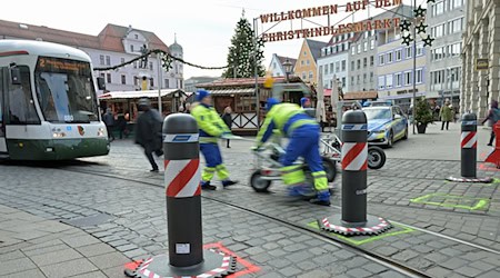 Zu den Hauptverkehrszeiten müssen Sicherheitsmitarbeiter neben dem Augsburger Christkindlesmarkt jede Stunde dutzendfach schwere Poller bewegen, damit die Straßenbahnen durchfahren können. / Foto: Malin Wunderlich/dpa