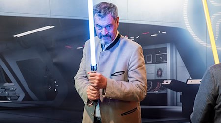 Wohl keine Waffe für den politischen Nahkampf: Markus Söder hält ein Lichtschwert. (Archivbild) / Foto: Daniel Vogl/dpa