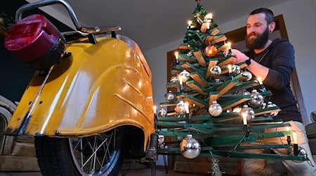 Jan Hofmann schmückt einen Weihnachtsbaum auch mit Weihnachtsbaumkugeln aus Simson-Blinkern. / Foto: Martin Schutt/dpa