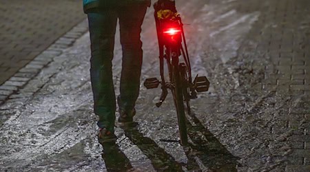 Ein Mann schiebt sein Fahrrad auf einer vereisten Straße. / Foto: Armin Weigel/dpa