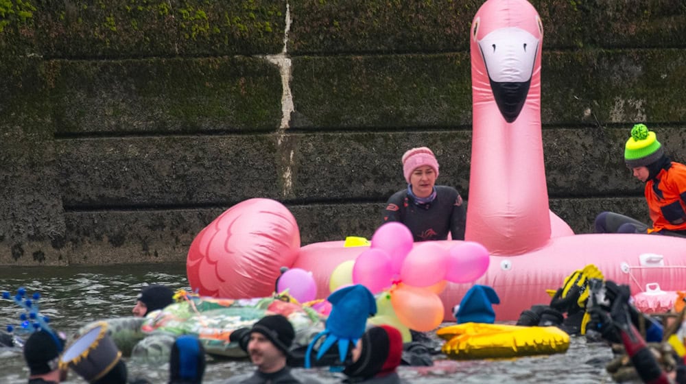 Teils bunt kostümiert schwimmen in und auf der eiskalten Donau Rettungsschwimmer.  / Foto: Stefan Puchner/dpa