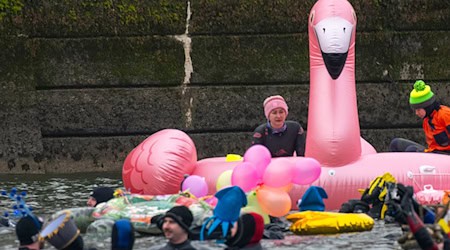 Teils bunt kostümiert schwimmen in und auf der eiskalten Donau Rettungsschwimmer.  / Foto: Stefan Puchner/dpa