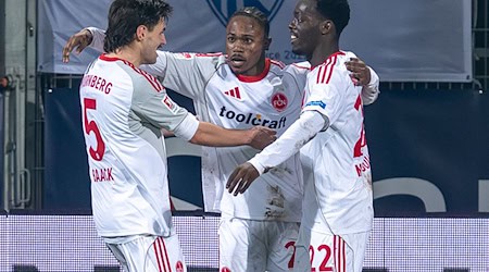 Der Nürnberger Mohamed Alì Zoma (Mitte) bejubelt mit den Vorlagengebern Tom Baack (links) und Rabby Nzingoula seinen Treffer zur 1:0-Führung. / Foto: David Inderlied/dpa