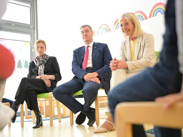 Bunte Regenbögen an der Wand und ein Stuhlkreis: In dieser Umgebung stellen sich Karin Prien, Markus Söder und Ulrike Scharf den Fragen von Vorschulkindern. / Foto: Malin Wunderlich/dpa
