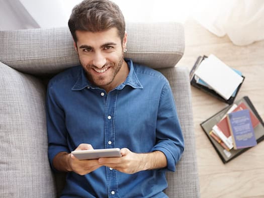 Mann nutzt Tablet für Online-Slots im Wohnzimmer