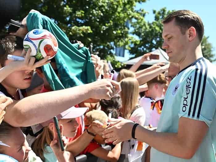 Manuel Neuer schreibt Autogramme für die DFB-Fans.  / Foto: Federico Gambarini/dpa