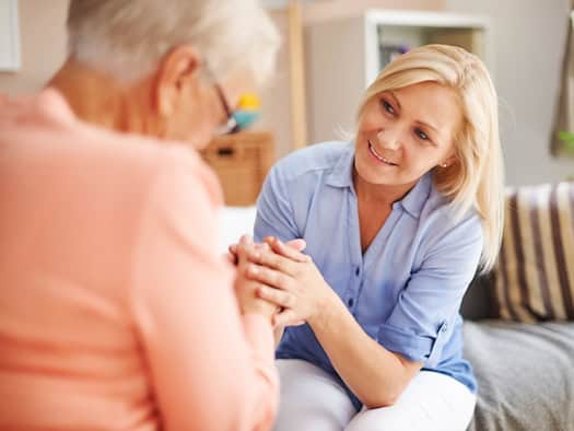 Pflegekraft einer 24-Stunden-Pflege hält die Hand einer Seniorin