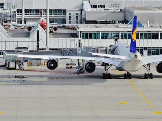 Flugzeug am Flughafen München mit angeschlossener Gangway und Terminal im Hintergrund.