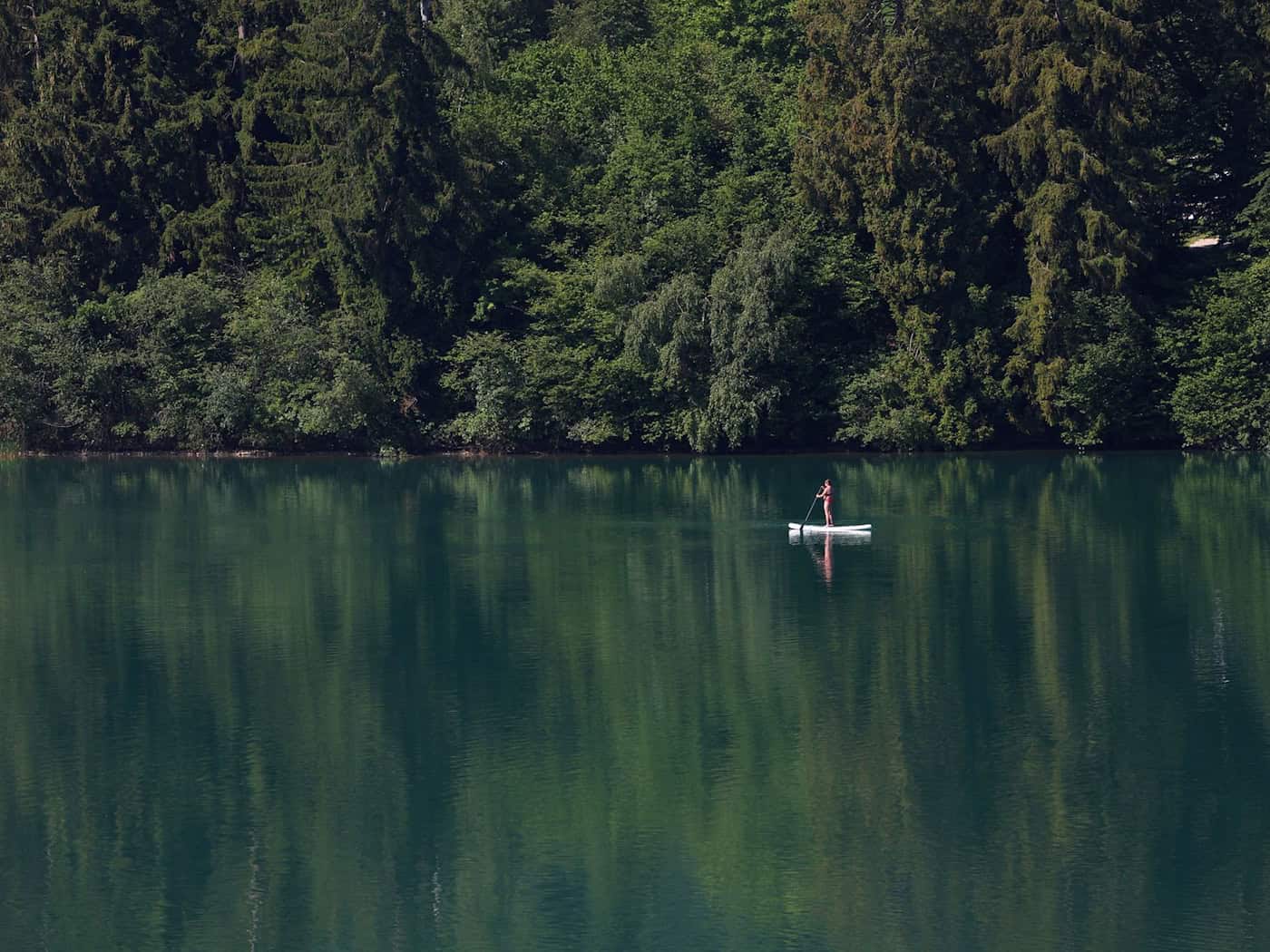 Eine Frau paddelt auf einem Stand-up-Paddle-Board über den Forggensee.  / Foto: Karl-Josef Hildenbrand/dpa