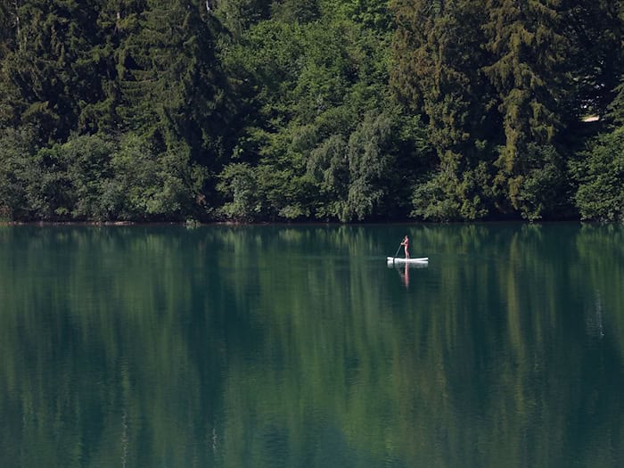 Eine Frau paddelt auf einem Stand-up-Paddle-Board über den Forggensee.  / Foto: Karl-Josef Hildenbrand/dpa