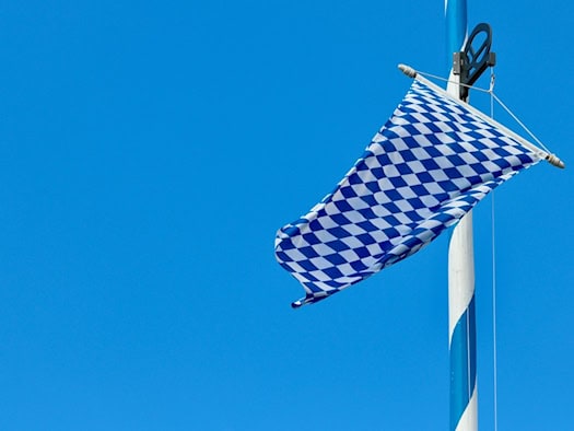 Bayerische Rautenflagge weht am blauen Himmel – Symbol für Tradition und regionale Identität.