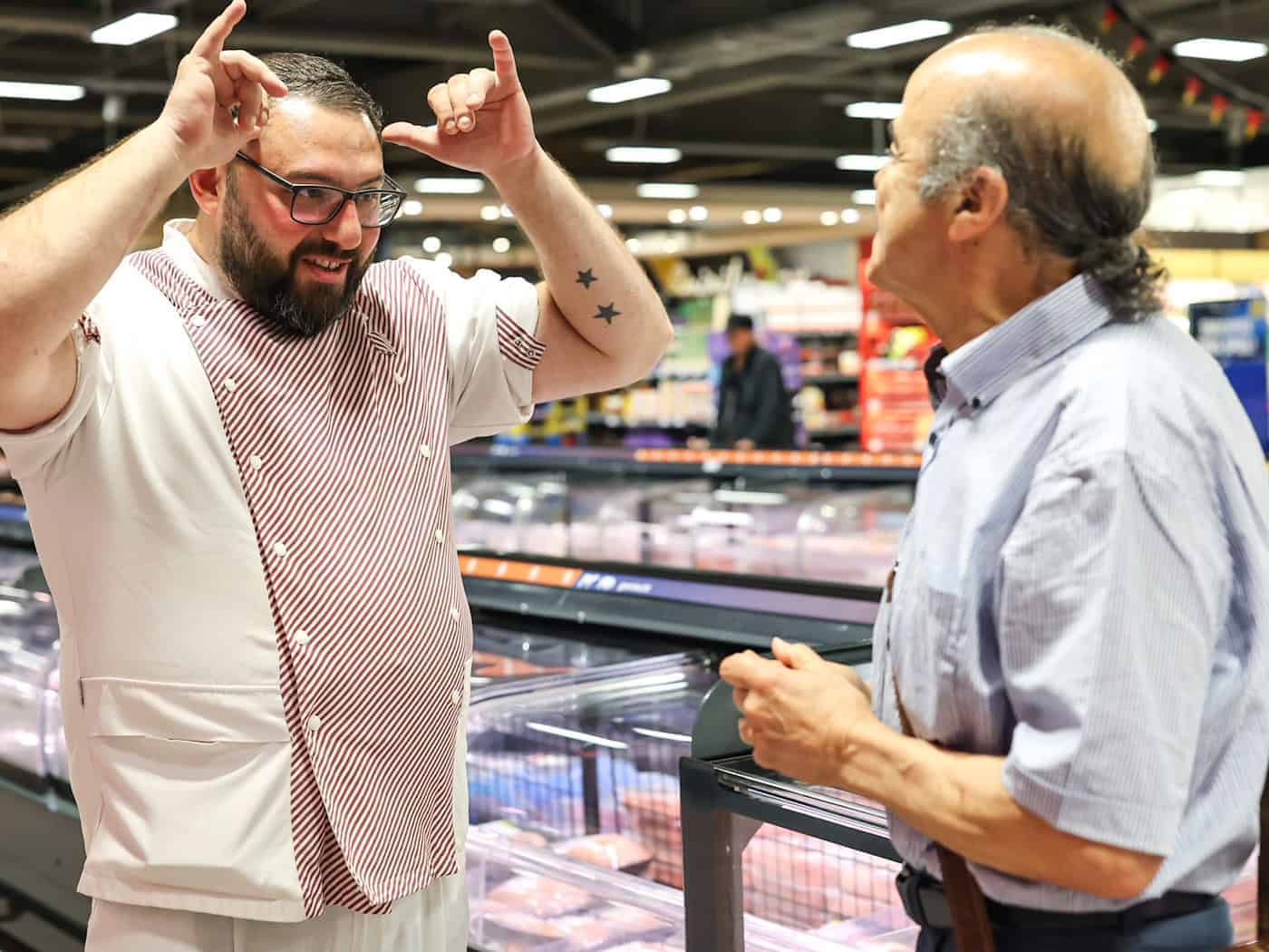 Metzger Yevgeniy Klibanov zeigt die Gebärde für «Rind».  / Foto: Daniel Löb/dpa