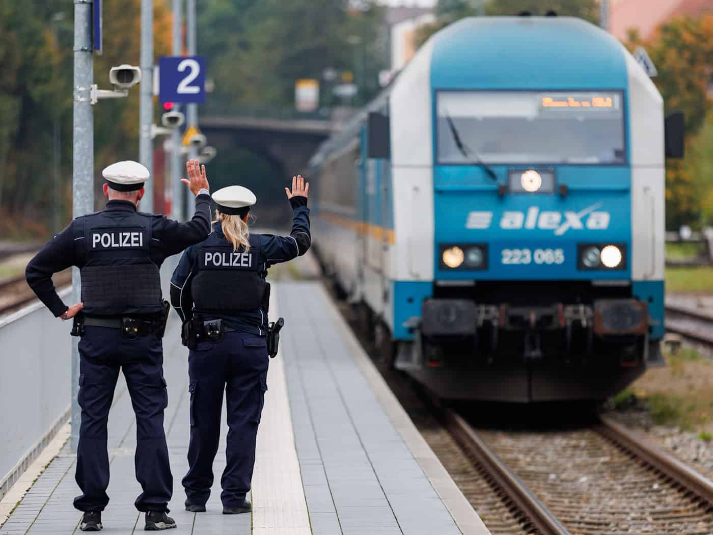 Bundespolizisten weisen per Handzeichen den Lokführer eines Zuges aus Prag in Richtung München darauf hin, dass sie zur Kontrolle des Einreiseverkehrs zusteigen werden. (Archivbild) / Foto: Daniel Karmann/dpa