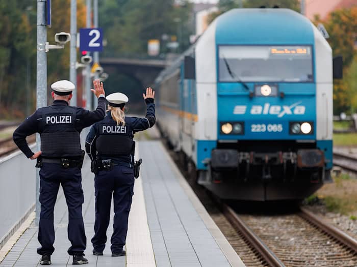 Bundespolizisten weisen per Handzeichen den Lokführer eines Zuges aus Prag in Richtung München darauf hin, dass sie zur Kontrolle des Einreiseverkehrs zusteigen werden. (Archivbild) / Foto: Daniel Karmann/dpa