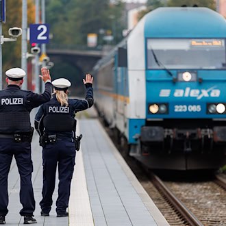 Bundespolizisten weisen per Handzeichen den Lokführer eines Zuges aus Prag in Richtung München darauf hin, dass sie zur Kontrolle des Einreiseverkehrs zusteigen werden. (Archivbild) / Foto: Daniel Karmann/dpa