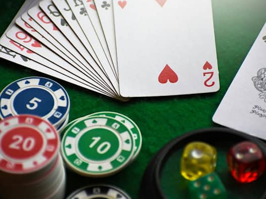 Spielkarten, Pokerchips und Würfel auf grünem Casinotisch