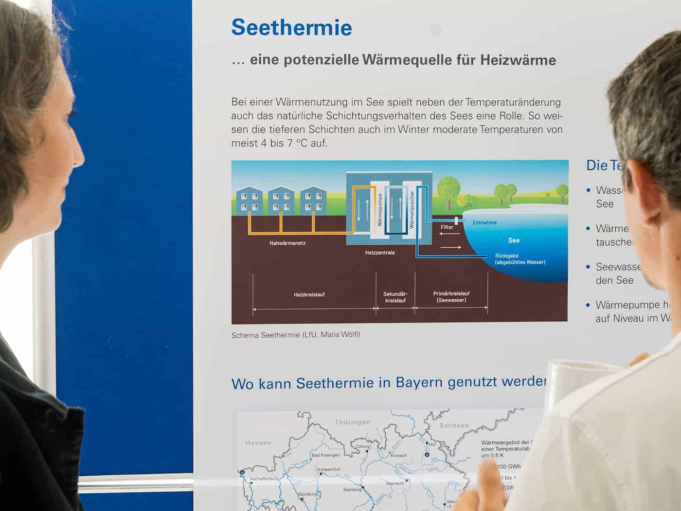 Besucher der Abschlussveranstaltung betrachten das Schema einer Seethermie-Anlage.  / Foto: Tobias Hase/dpa