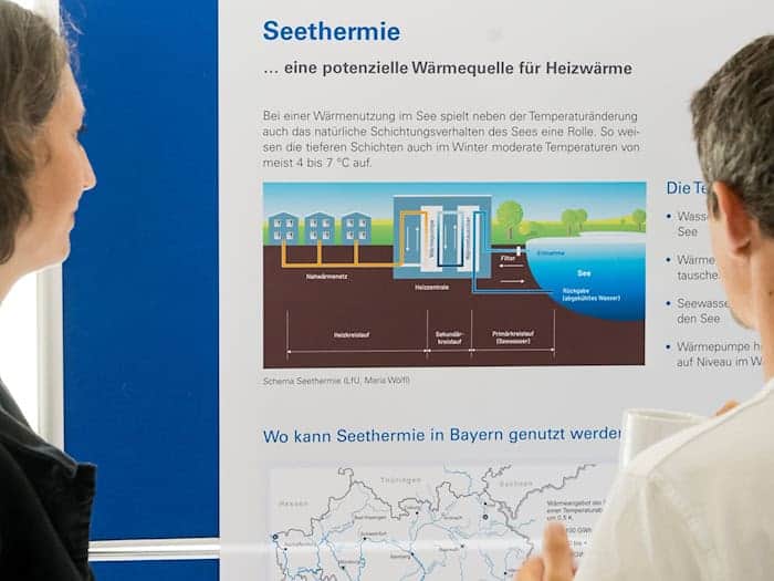 Besucher der Abschlussveranstaltung betrachten das Schema einer Seethermie-Anlage.  / Foto: Tobias Hase/dpa