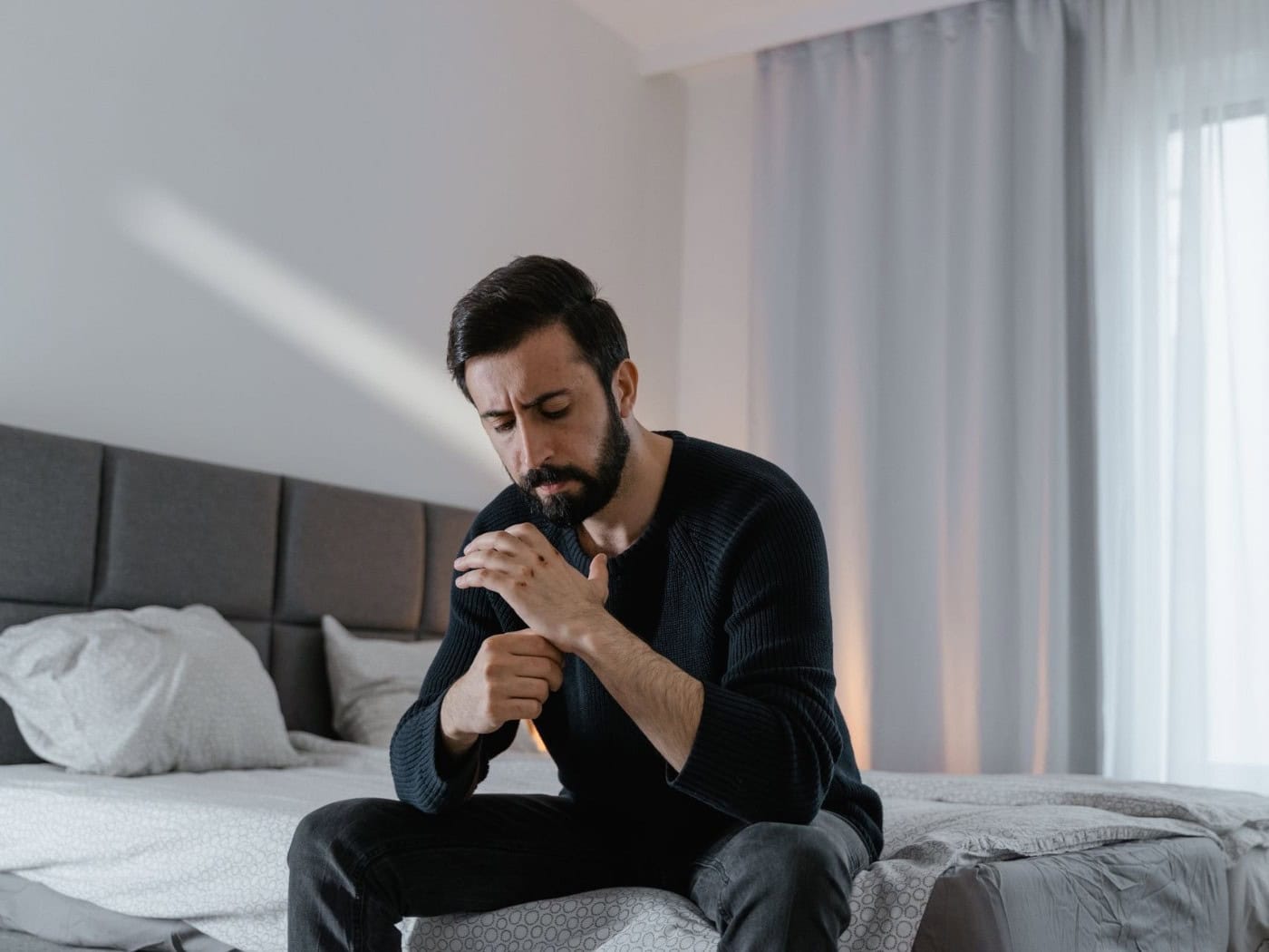 Mann sitzt nachdenklich auf dem Bett
