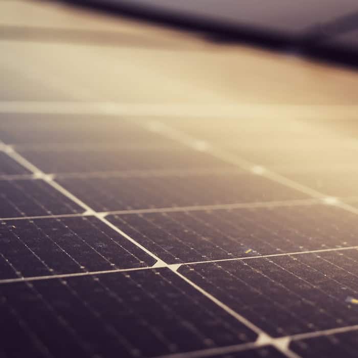 Nahaufnahme eines PV-Moduls mit sichtbaren Solarzellen, die im Sonnenlicht glänzen.