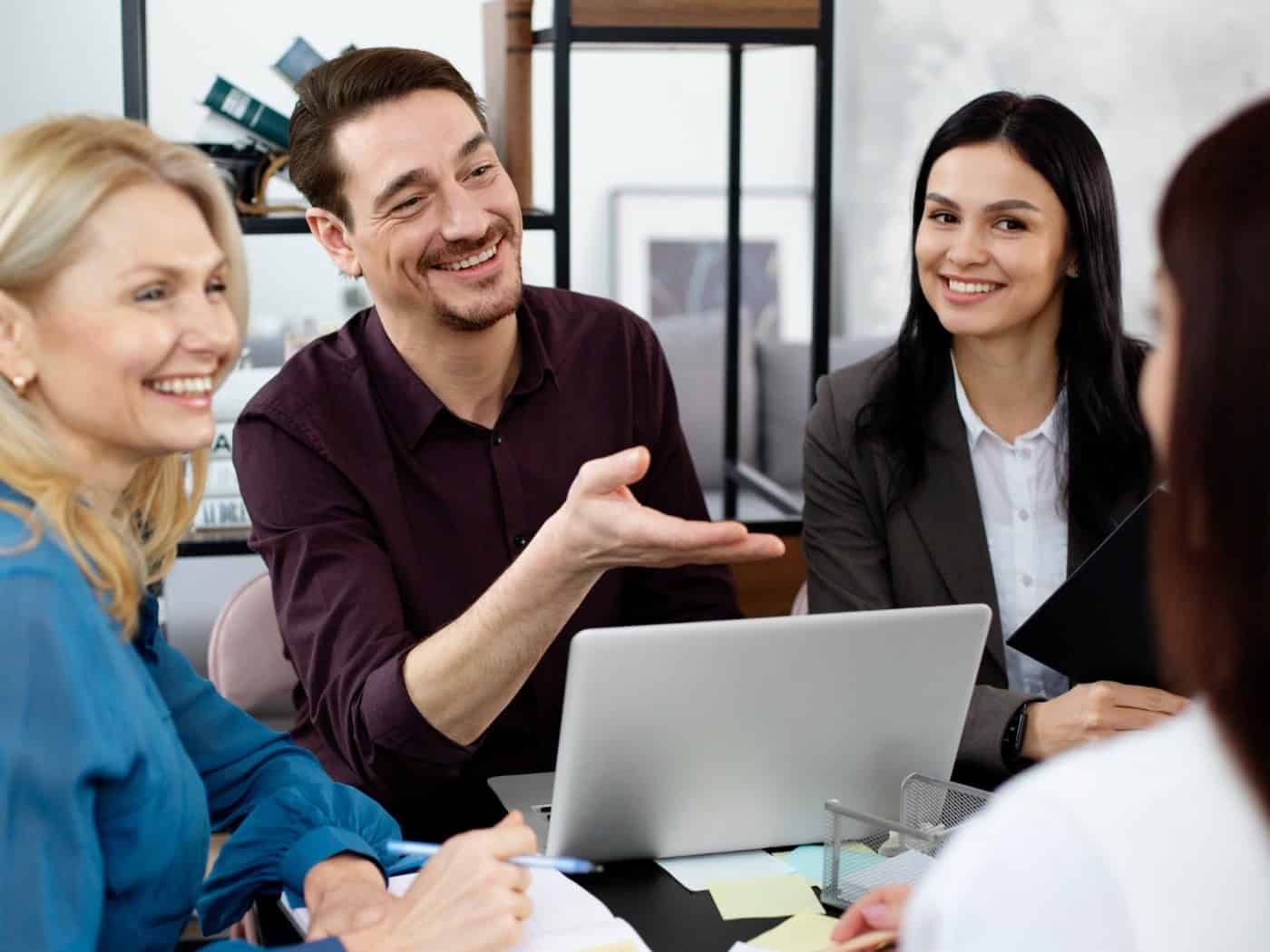 Engagiertes Team bei kreativer Besprechung im Büro, eine Person arbeitet am Laptop, eine andere präsentiert eine Idee