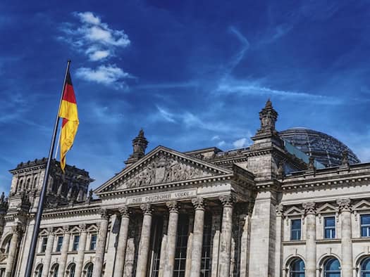 Reichstagsgebäude in Berlin mit deutscher Flagge und blauem Himmel