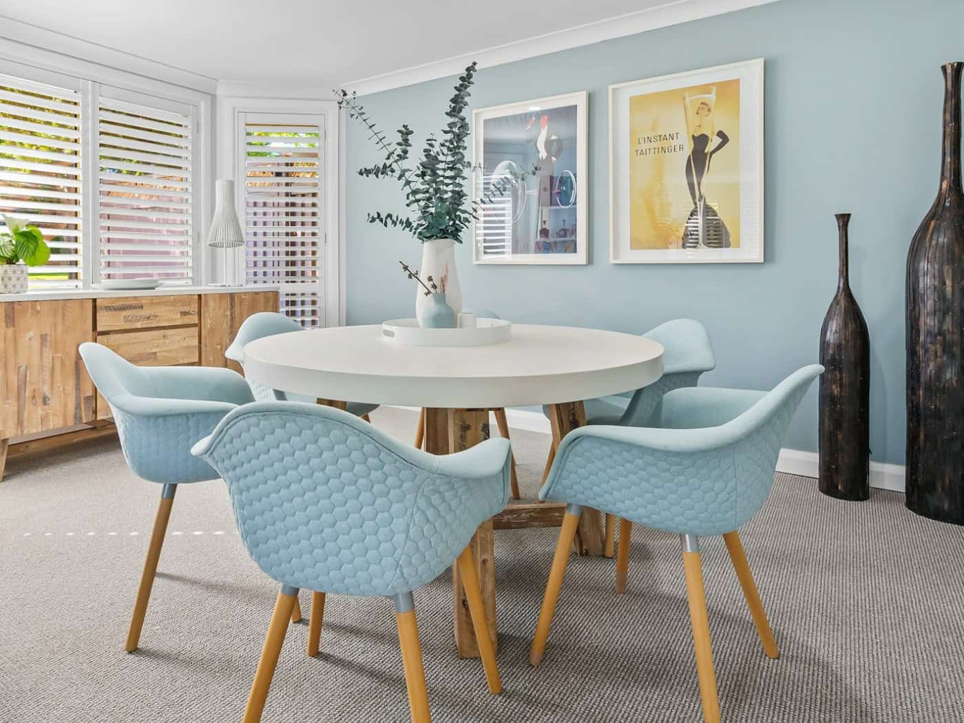 Modernes Esszimmer mit weißem rundem Esstisch und blauen Stühlen
