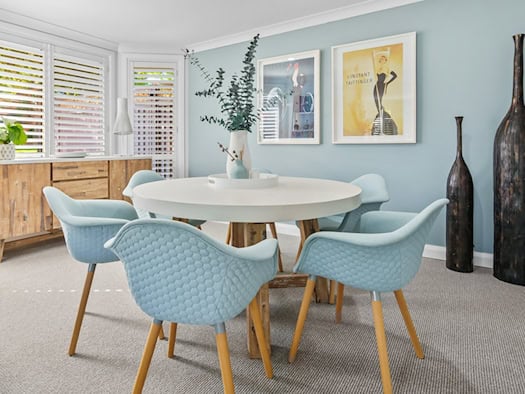Modernes Esszimmer mit weißem rundem Esstisch und blauen Stühlen