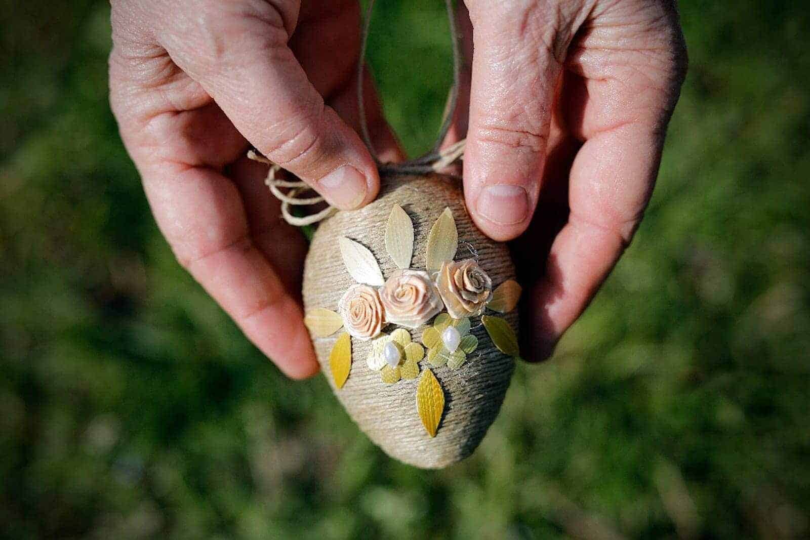 Hände einer älteren Dame halten verziertes Osterei in der Hand