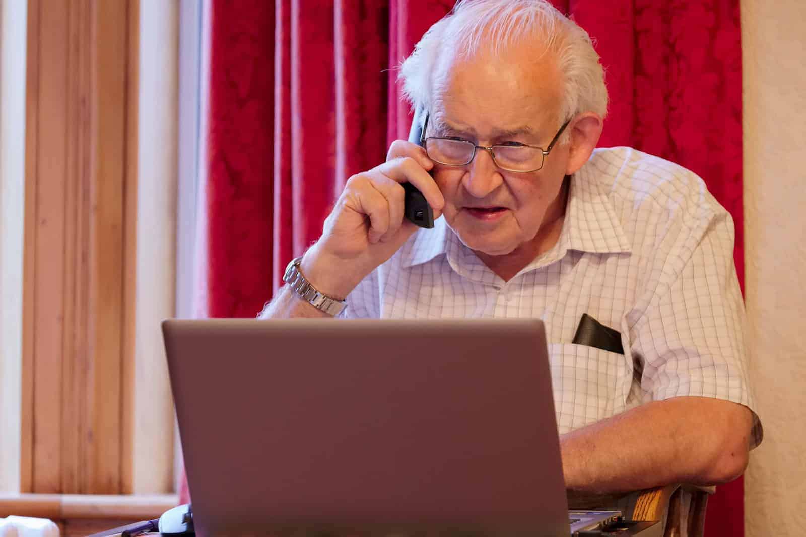 Rentner telefoniert und arbeitet am Computer