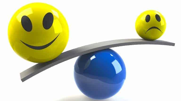 Lachender Smiley und trauriger Smiley auf einer Wippe