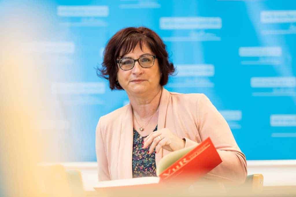 Versicherungsberaterin Heyer blättert in Broschüre.